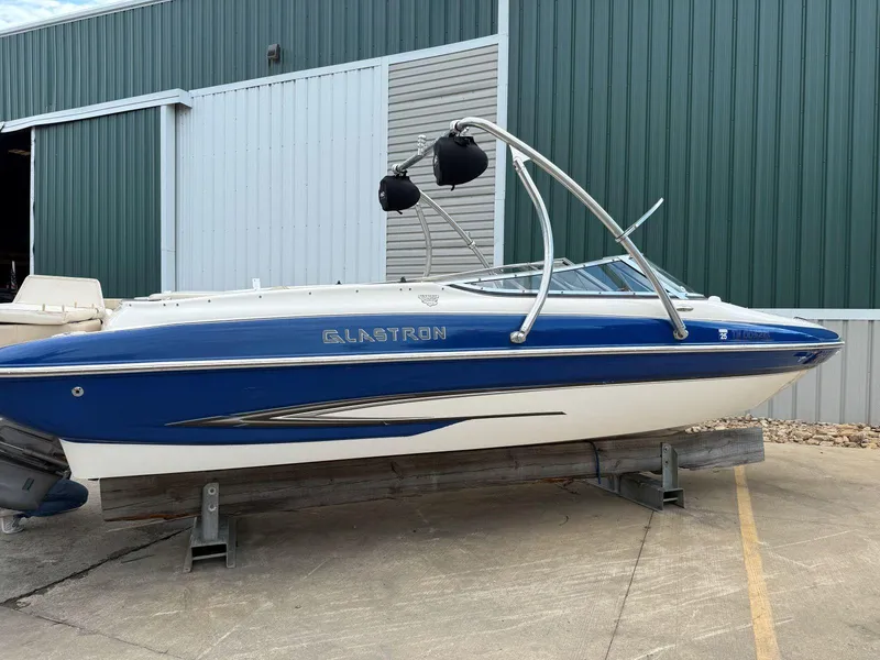 Slide: The Image of 2006 Glastron GX 235 boat with blue and white exterior, parked on a concrete surface. - 2