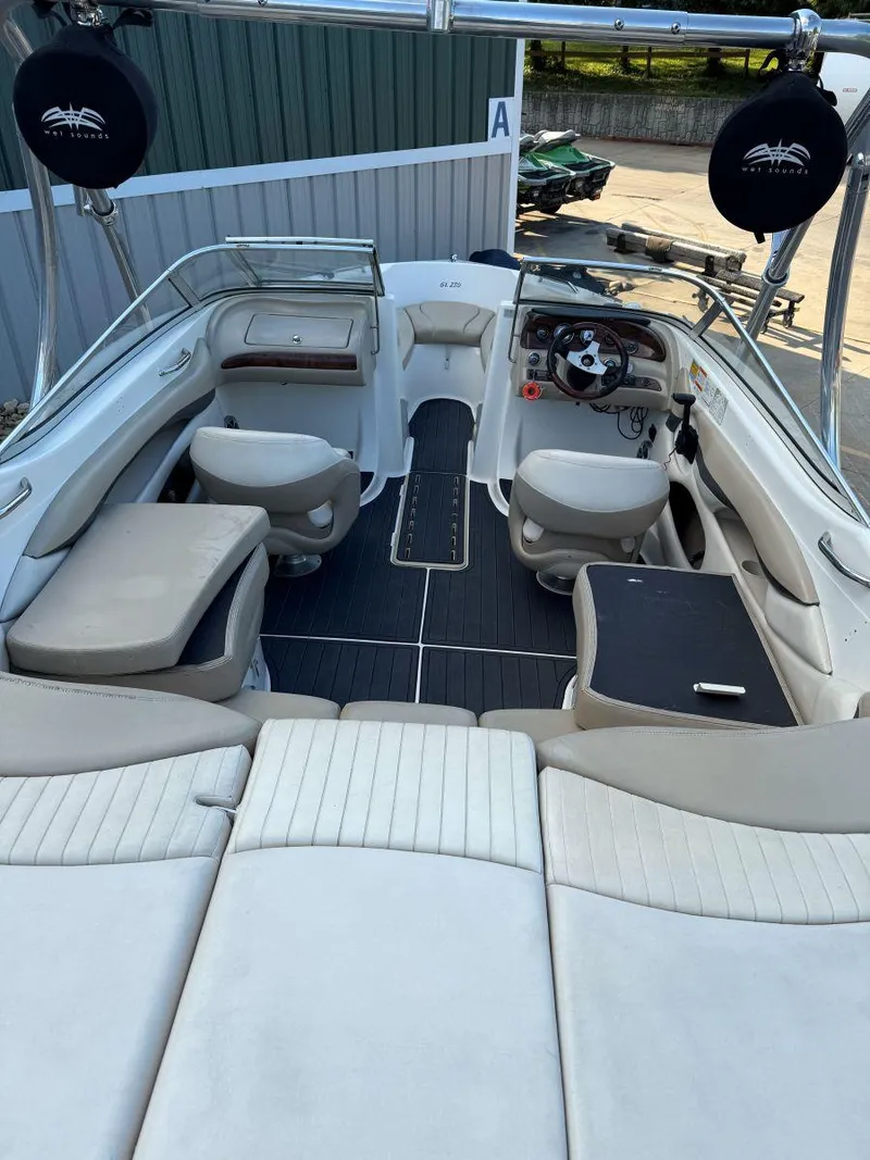 Slide: The Image of 2006 Glastron GX 235 boat interior with seating and steering wheel, docked outdoors. - 6