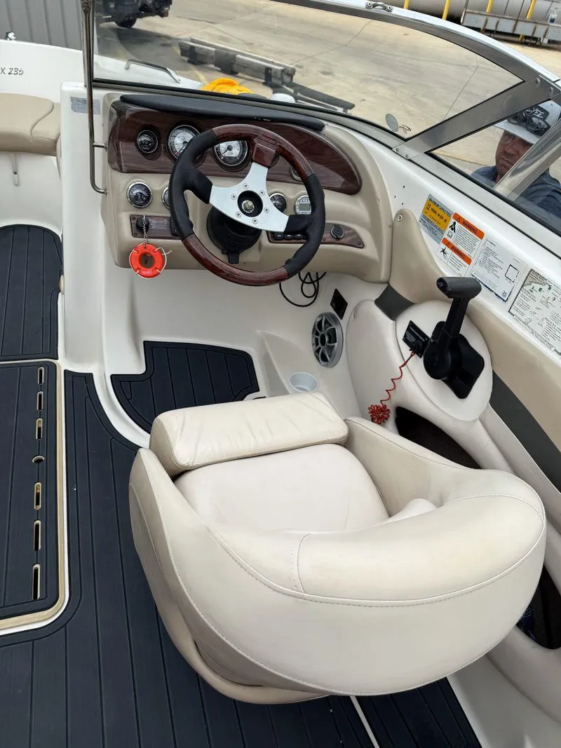 Slide: The Image of 2006 Glastron GX 235 boat interior with steering wheel and white captain's chair. - 9
