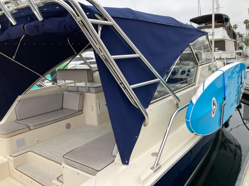 Slide: The Image of 2004 Mainship Pilot 34 boat with blue canopy and attached surfboard. - 16