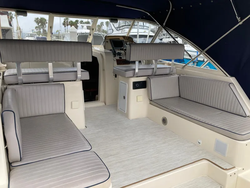 Slide: The Image of 2004 Mainship Pilot 34 interior with cushioned seating and helm, docked at marina. - 23