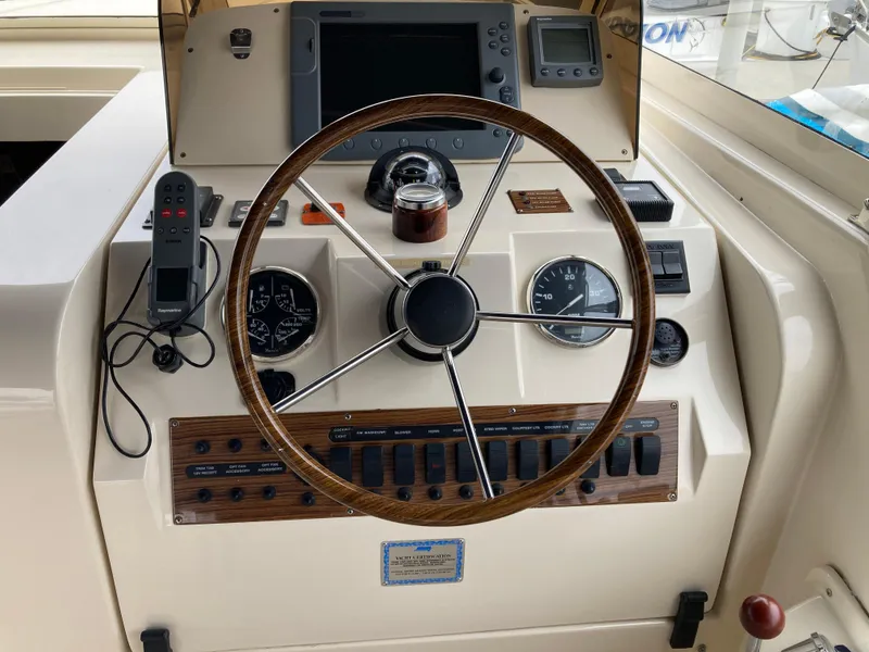 Slide: The Image of 2004 Mainship Pilot 34 helm with steering wheel, gauges, and navigation controls. - 26