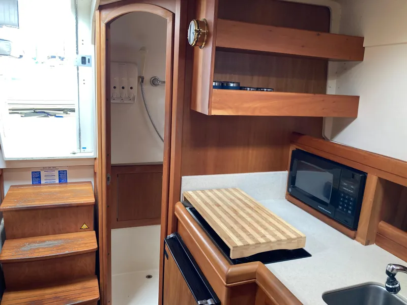 Slide: The Image of 2004 Mainship Pilot 34 interior with kitchenette, microwave, cutting board, and shower area. - 29