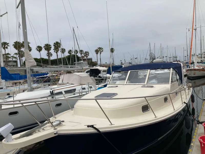 Slide: The Image of 2004 Mainship Pilot 34 docked at marina with sailboats and palm trees in background. - 3