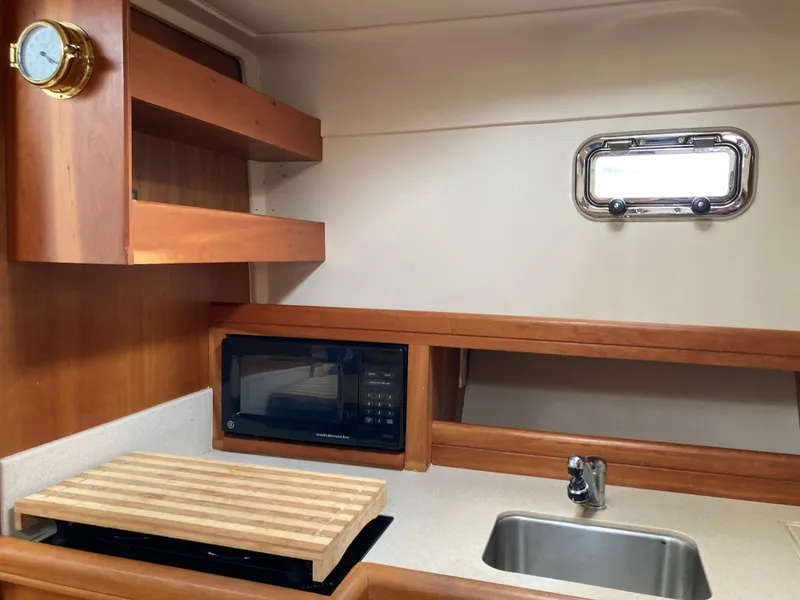 Slide: The Image of 2004 Mainship Pilot 34 galley with sink, microwave, and wooden shelves. - 30