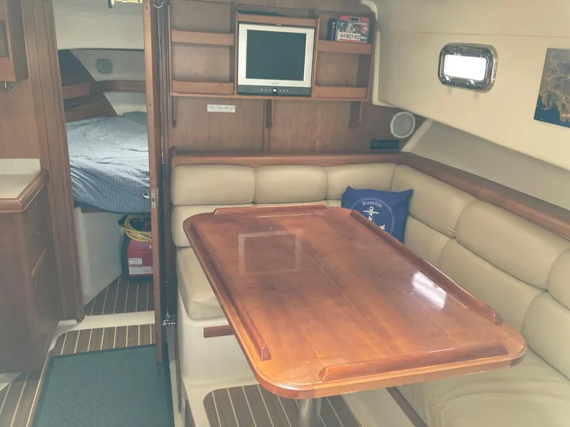 Slide: The Image of 2004 Mainship Pilot 34 interior with dining area, wood table, and cozy seating. - 33