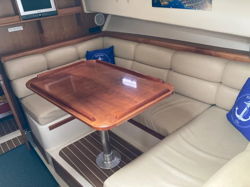 Slide: The Image of 2004 Mainship Pilot 34 interior with cushioned seating and wooden table. - 34