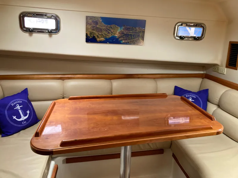 Slide: The Image of 2004 Mainship Pilot 34 interior with wooden table, beige seating, and nautical decor. - 35
