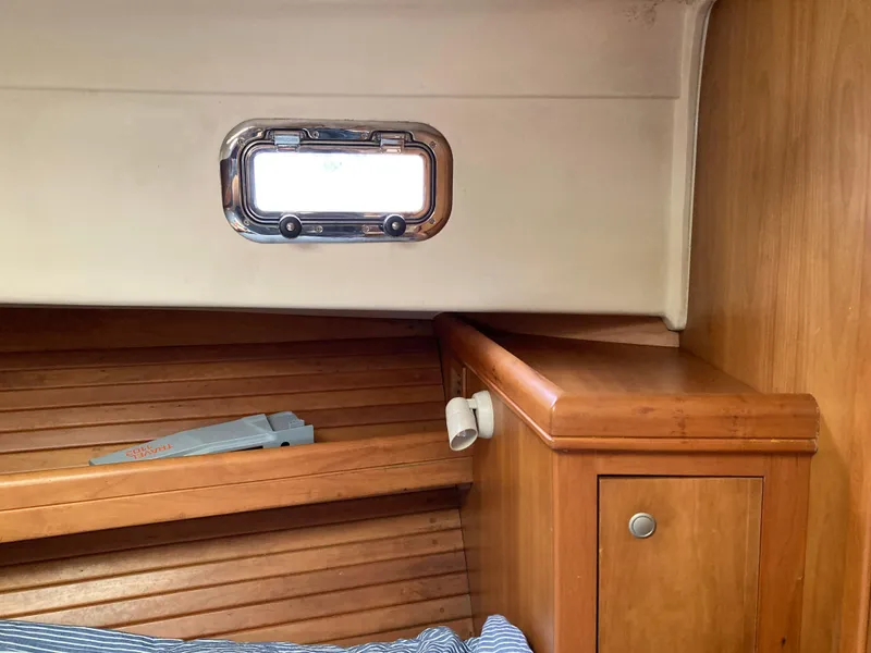 Slide: The Image of 2004 Mainship Pilot 34 cabin interior with wooden cabinetry and porthole window. - 42