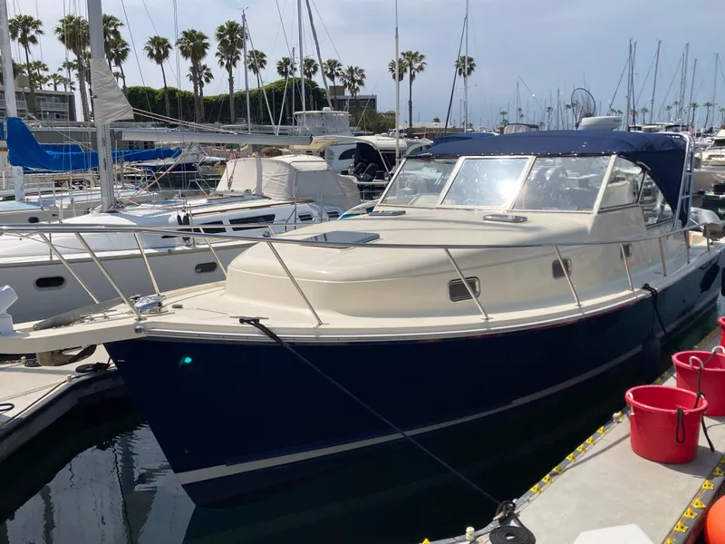 Slide: The Image of 2004 Mainship Pilot 34 boat docked in marina with palm trees in background. - 6