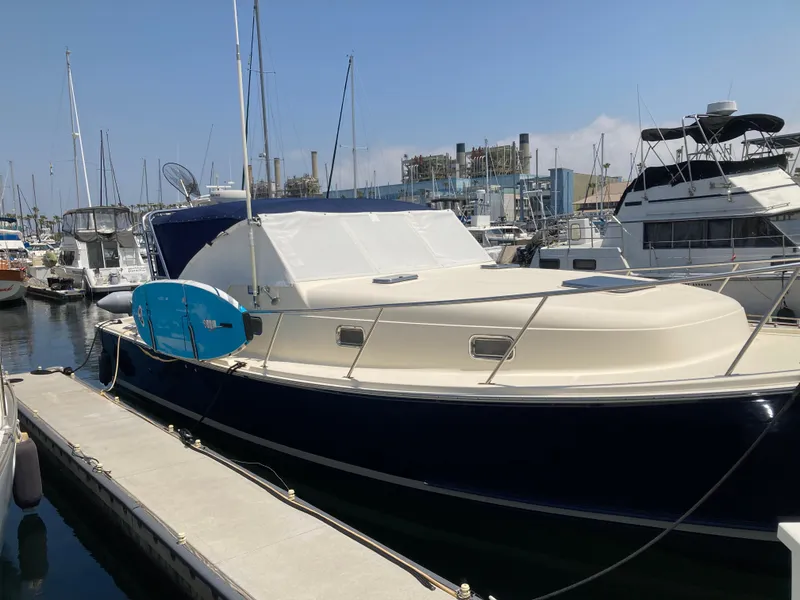 Slide: The Image of 2004 Mainship Pilot 34 docked at marina, featuring sleek design and blue hull. - 9