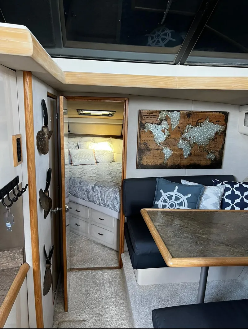 Slide: The Image of 1990 Bayliner 4387 Aft Cabin interior with cozy seating, nautical decor, and bedroom view. - 13