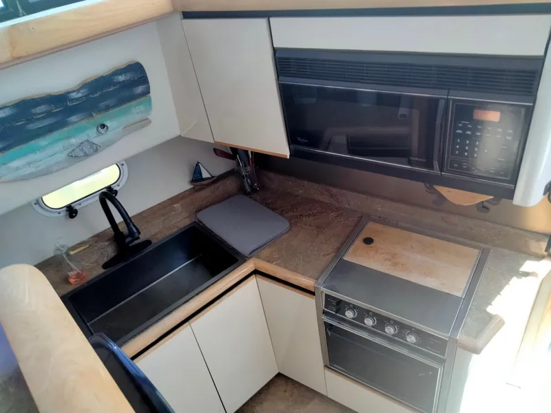 Slide: The Image of 1990 Bayliner 4387 Aft Cabin kitchen with sink, stove, and microwave. - 15