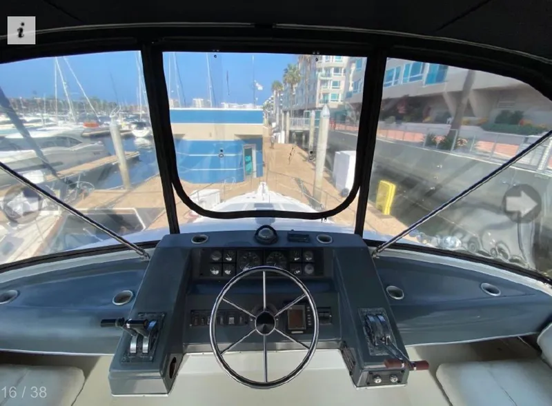 Slide: The Image of 1990 Bayliner 4387 Aft Cabin helm with marina view through large windows. - 17