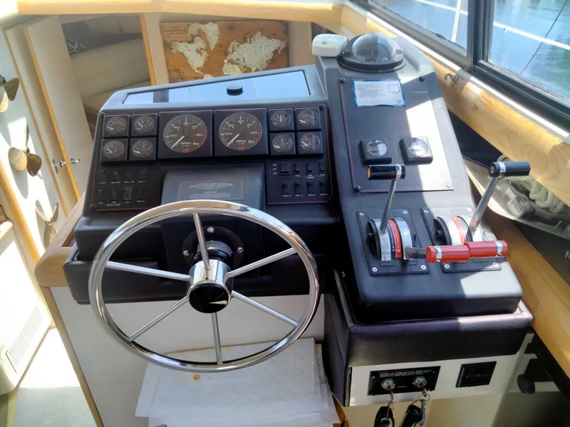 Slide: The Image of 1990 Bayliner 4387 Aft Cabin helm with steering wheel, gauges, and throttle controls. - 18