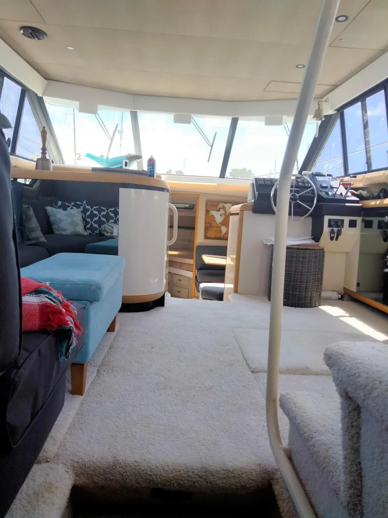 Slide: The Image of Interior of 1990 Bayliner 4387 Aft Cabin with seating and helm, featuring large windows. - 23