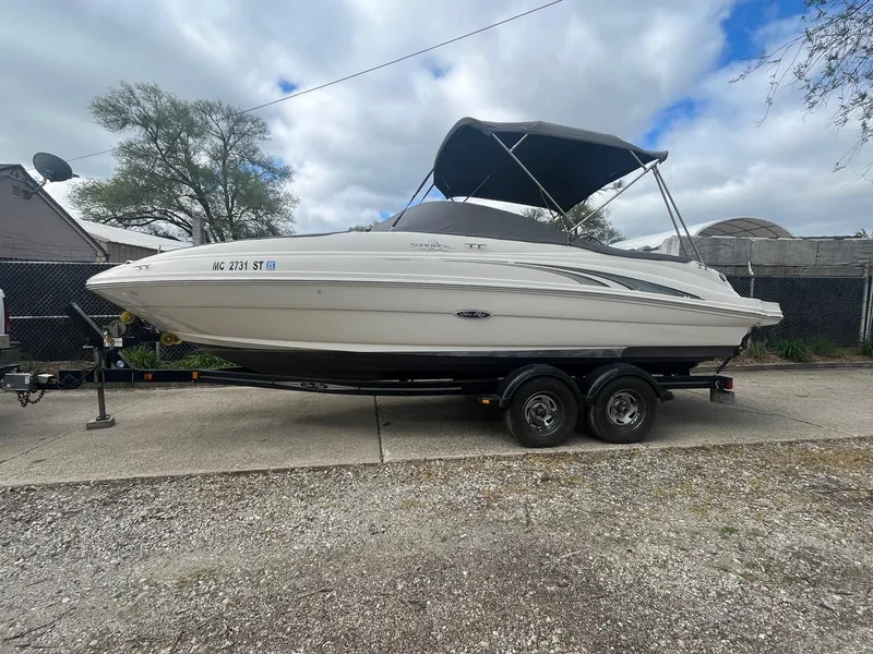 Slide: The Image of 2004 Sea Ray 220 Sundeck boat on trailer, parked outdoors under cloudy sky. - 0
