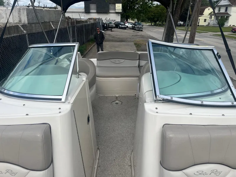 Slide: The Image of 2004 Sea Ray 220 Sundeck boat with open seating and windshield, parked on a street. - 13
