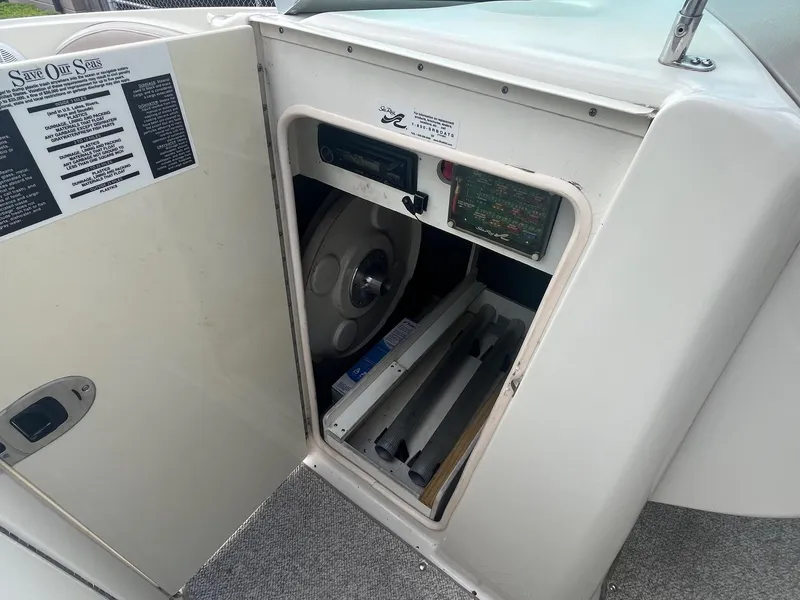 Slide: The Image of 2004 Sea Ray 220 Sundeck storage compartment with steering wheel and equipment. - 17