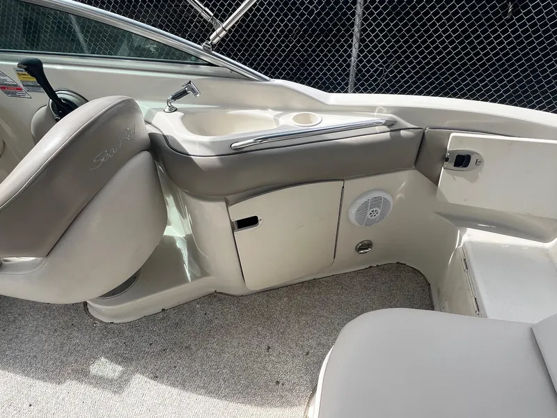 Slide: The Image of 2004 Sea Ray 220 Sundeck interior with beige seating and built-in storage. - 20