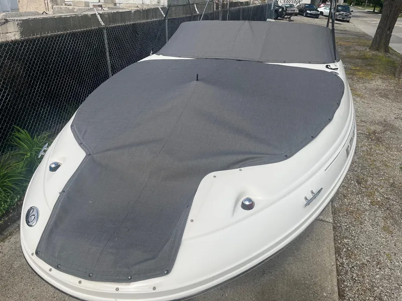 Slide: The Image of 2004 Sea Ray 220 Sundeck boat with gray cover, parked on a concrete surface. - 9