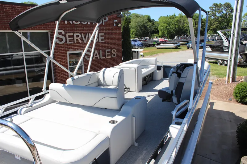 Slide: The Image of 2025 Tahoe Pontoon Sport 85 Versatile Rear Bench, displayed outdoors near a service and sales building. - 6