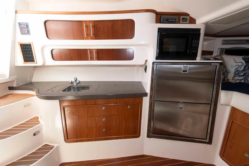 Slide: The Image of 2006 Grady-White Express 360 interior kitchen with wood cabinets, stainless steel appliances, and compact design. - 22