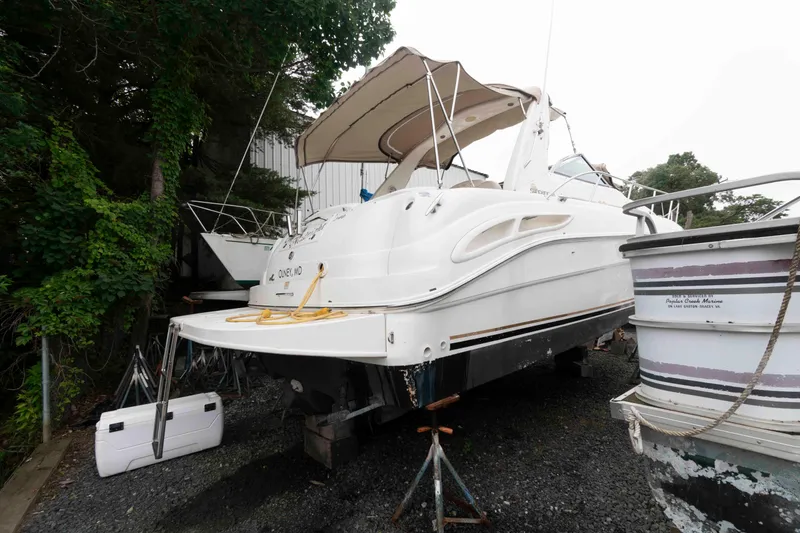 Slide: The Image of 2001 Sea Ray 340 Sundancer boat on dry dock, surrounded by trees and other vessels. - 2