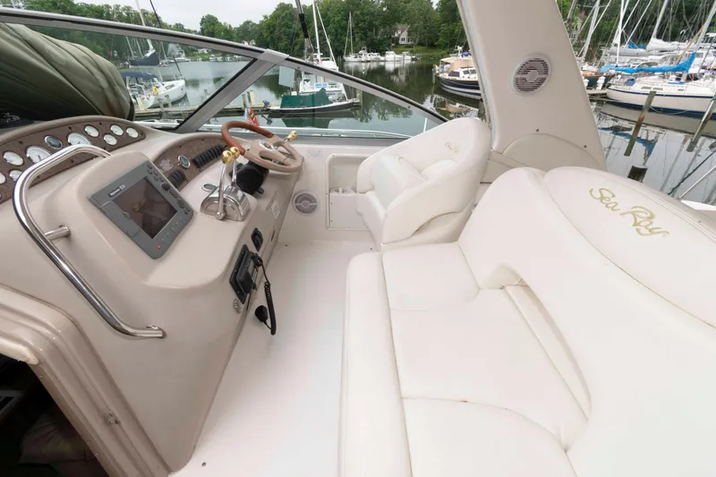Slide: The Image of 2001 Sea Ray 340 Sundancer cockpit with white seating and control panel, docked at marina. - 4