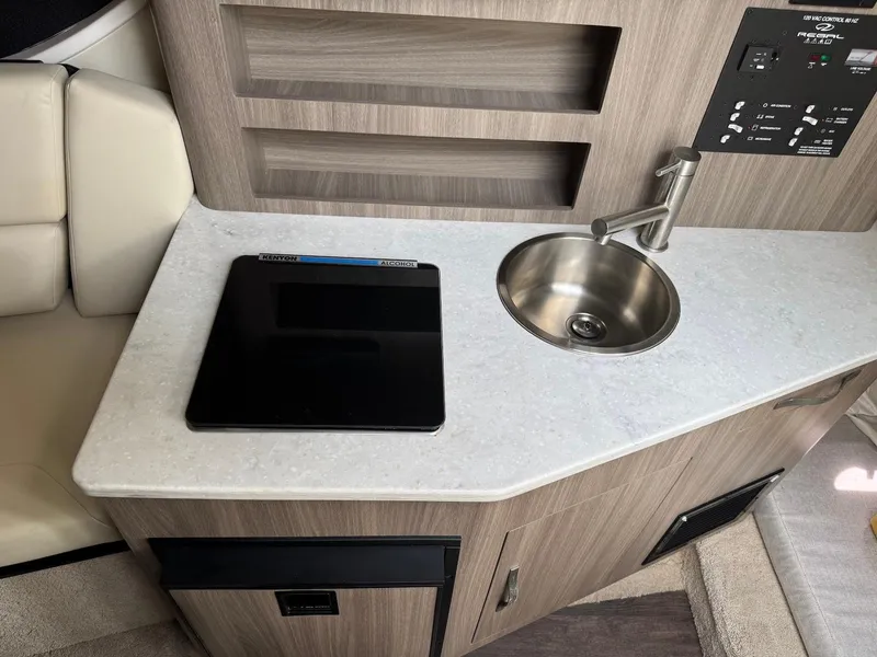 Slide: The Image of 2019 Regal 26 XO boat interior with sink and stove in compact kitchen area. - 14