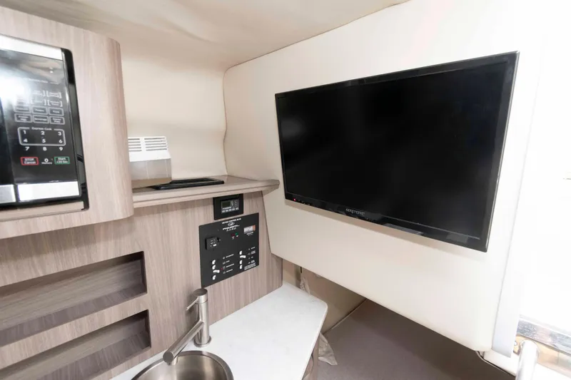Slide: The Image of 2019 Regal 26 XO interior with TV, microwave, and sink in compact cabin space. - 16