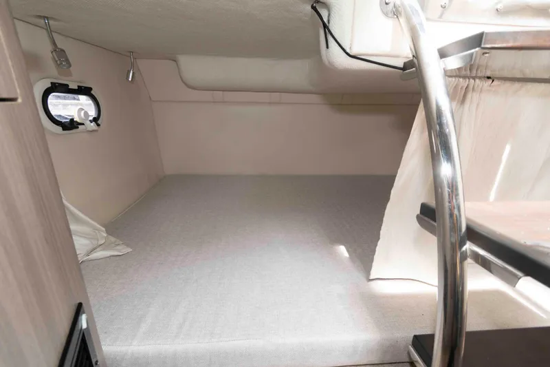 Slide: The Image of 2019 Regal 26 XO cabin interior with bed, porthole, and ladder. - 17