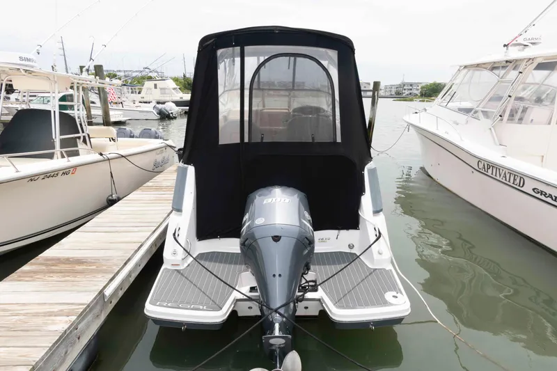 Slide: The Image of 2019 Regal 26 XO boat docked with black canopy and outboard motor. - 2