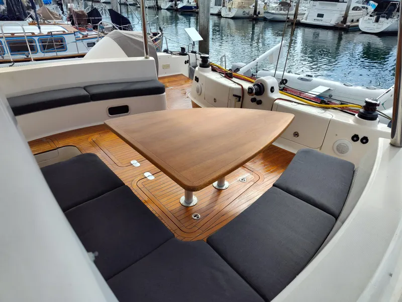 Slide: The Image of Spacious seating area on a 2011 Performance Catamarans 52, featuring a wooden table and marina view. - 32