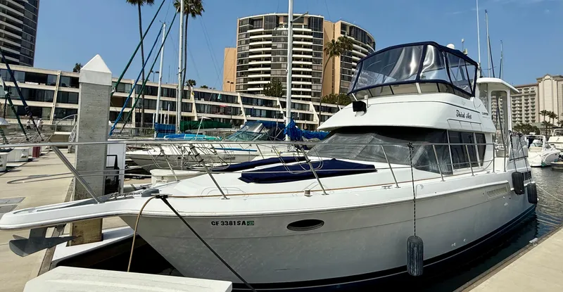 The Image of 1997 Carver 355 Aft Cabin yacht docked at marina with modern buildings in background. - 1