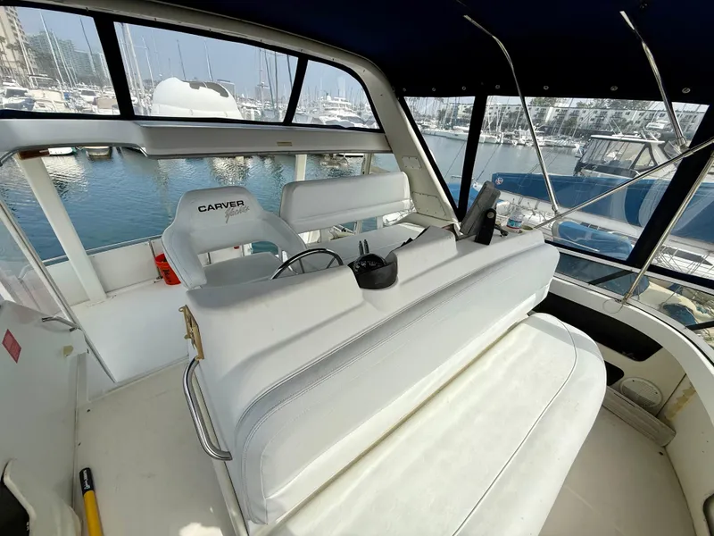 Slide: The Image of 1997 Carver 355 Aft Cabin yacht interior with white seating and marina view. - 11
