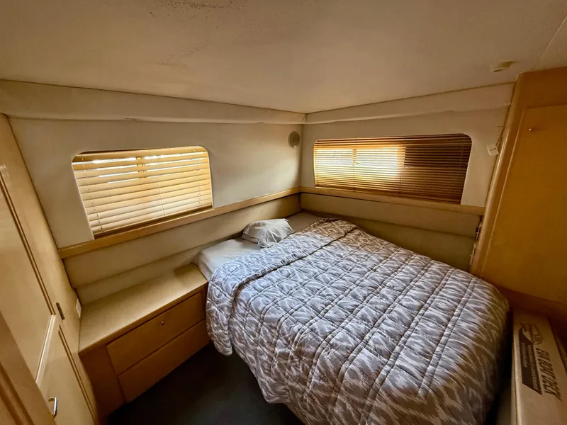 Slide: The Image of 1997 Carver 355 Aft Cabin bedroom with cozy bed, wooden blinds, and soft lighting. - 16