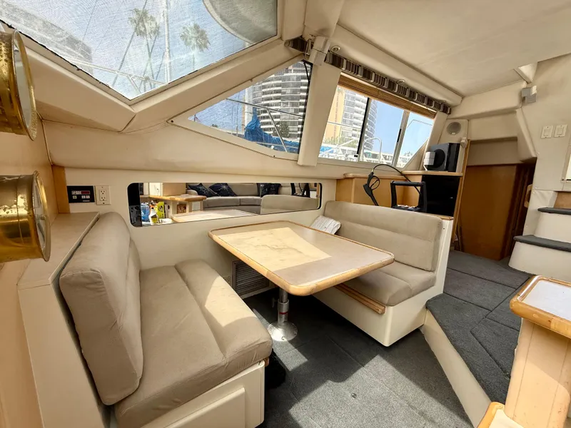 Slide: The Image of 1997 Carver 355 Aft Cabin interior with dining area, beige seating, and large windows. - 18