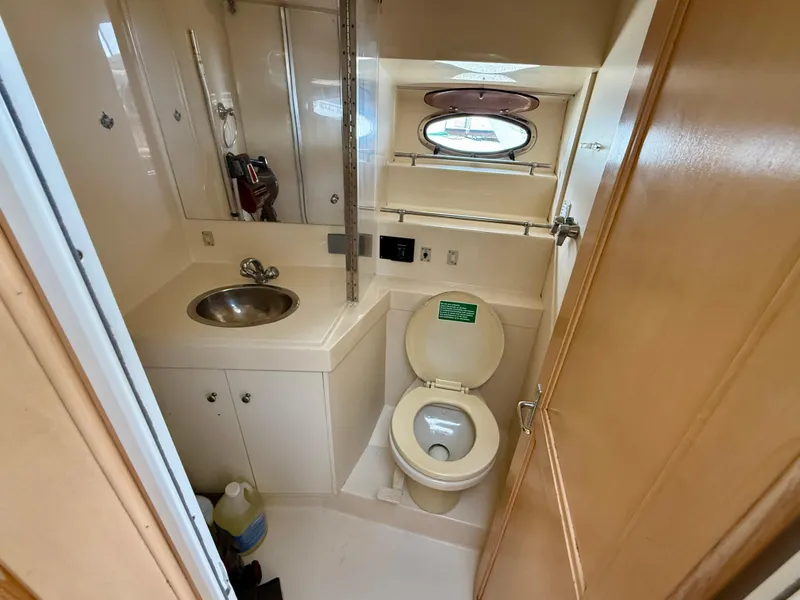 Slide: The Image of 1997 Carver 355 Aft Cabin bathroom with sink, toilet, and porthole window. - 21