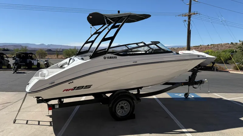 Slide: The Image of 2025 Yamaha Boats AR195 on trailer, parked outdoors under clear blue sky. - 18