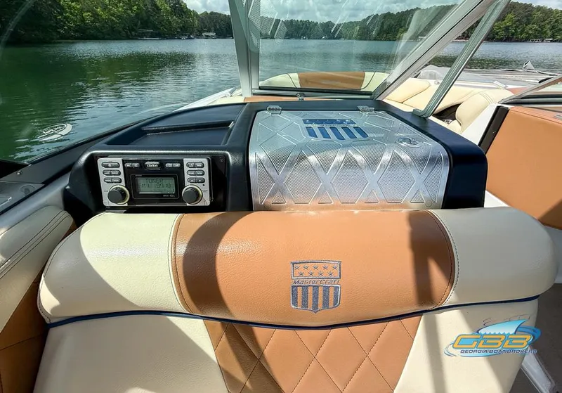Slide: The Image of 2013 MasterCraft X-45 boat interior with tan leather seats and audio system, on a serene lake. - 17