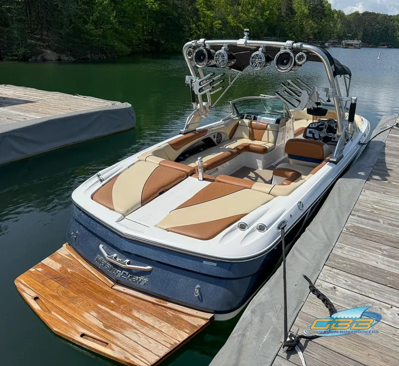 Slide: The Image of 2013 MasterCraft X-45 boat docked on a serene lake with lush greenery. - 6