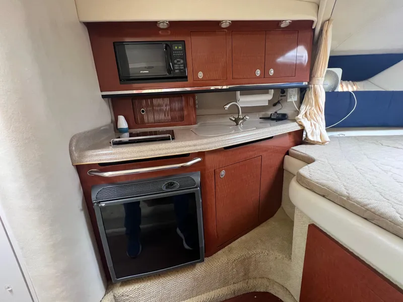 Slide: The Image of 2005 Sea Ray 290 Amberjack interior with kitchenette, featuring microwave, sink, and mini-fridge. - 14