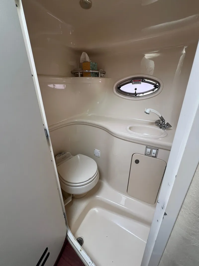 Slide: The Image of 2005 Sea Ray 290 Amberjack bathroom with toilet, sink, and porthole window. - 17