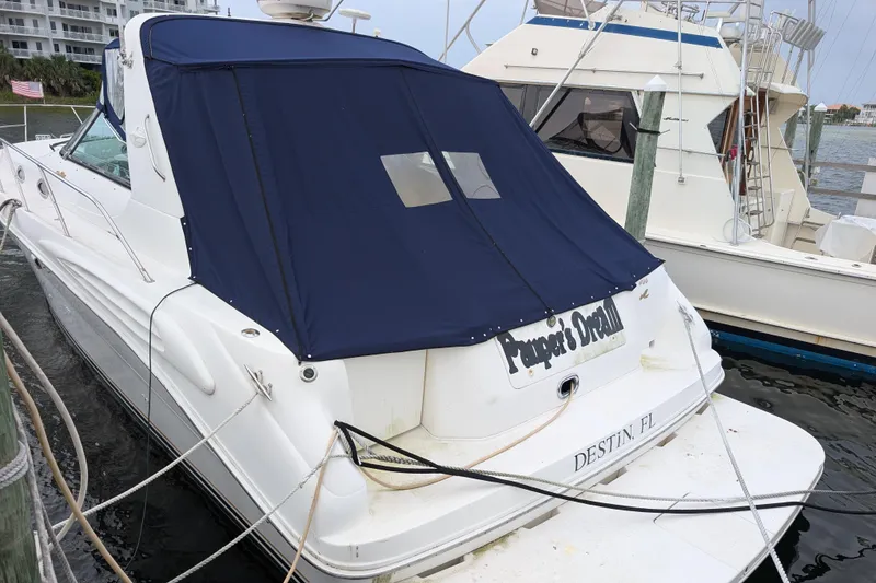 Slide: The Image of 1998 Sea Ray 400 Sundancer docked, featuring a blue cover and visible stern. - 10