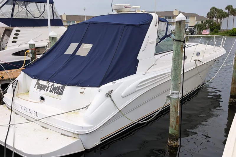 Slide: The Image of 1998 Sea Ray 400 Sundancer docked, featuring a blue canvas cover, in a marina setting. - 19