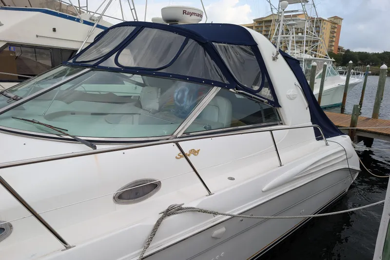 Slide: The Image of 1998 Sea Ray 400 Sundancer yacht docked at marina, featuring sleek design and blue canopy. - 2
