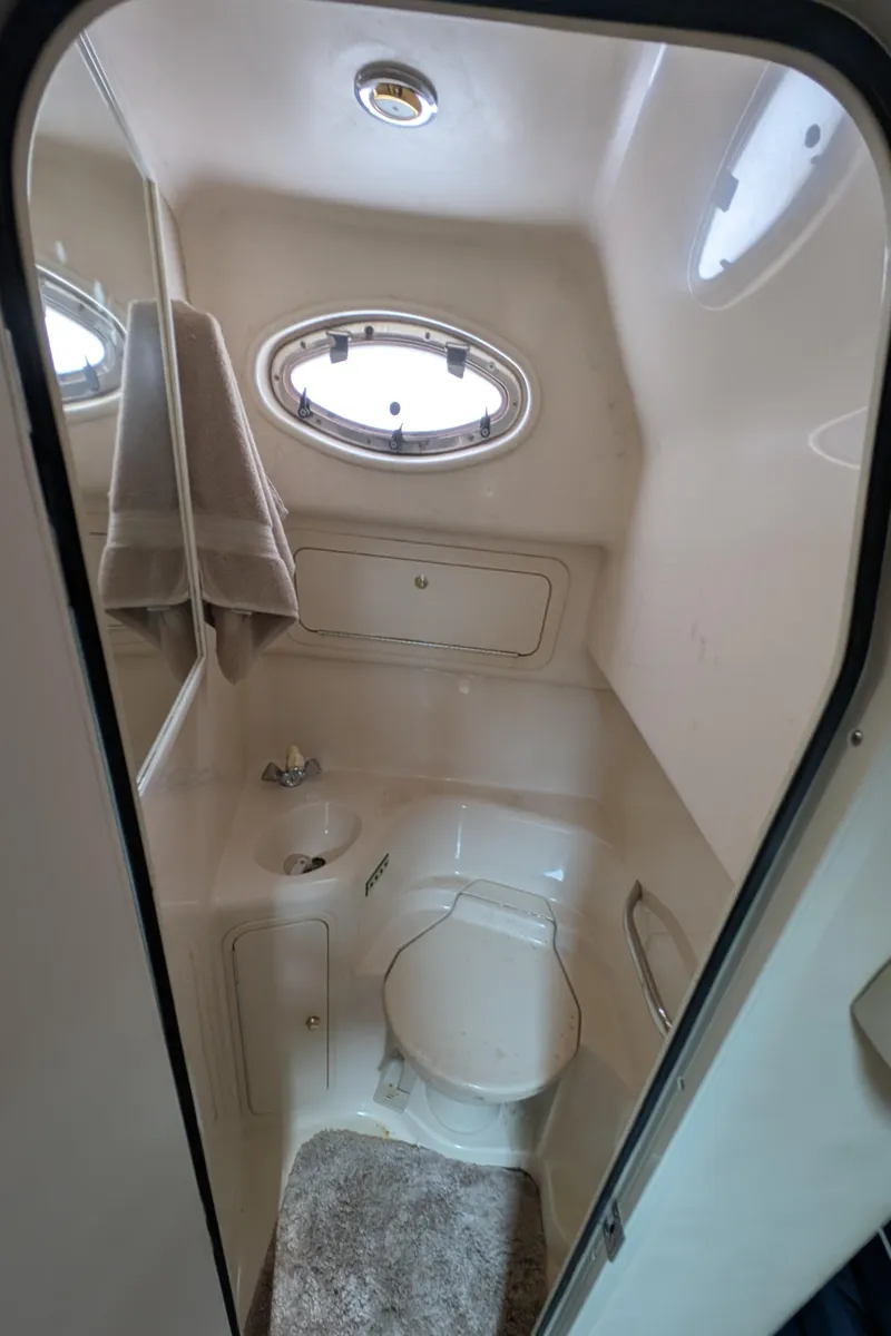 Slide: The Image of 1998 Sea Ray 400 Sundancer bathroom with oval window and compact design. - 23