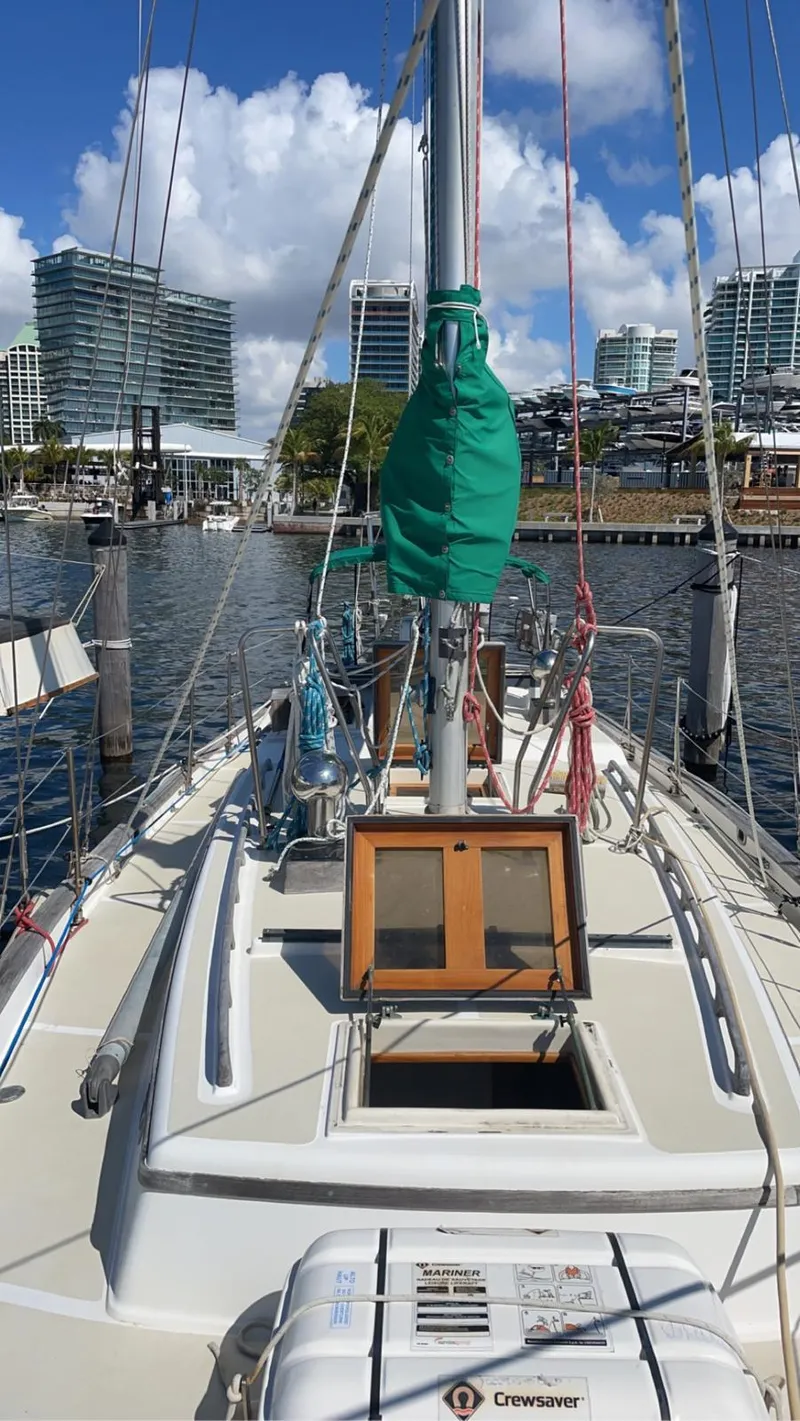 Slide: The Image of 1986 Cabo Rico CB38 sailboat docked in marina, city skyline in background, clear sky. - 1