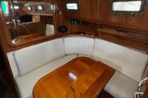 Slide: The Image of 1986 Cabo Rico CB38 yacht interior with wooden table and white cushioned seating. - 11